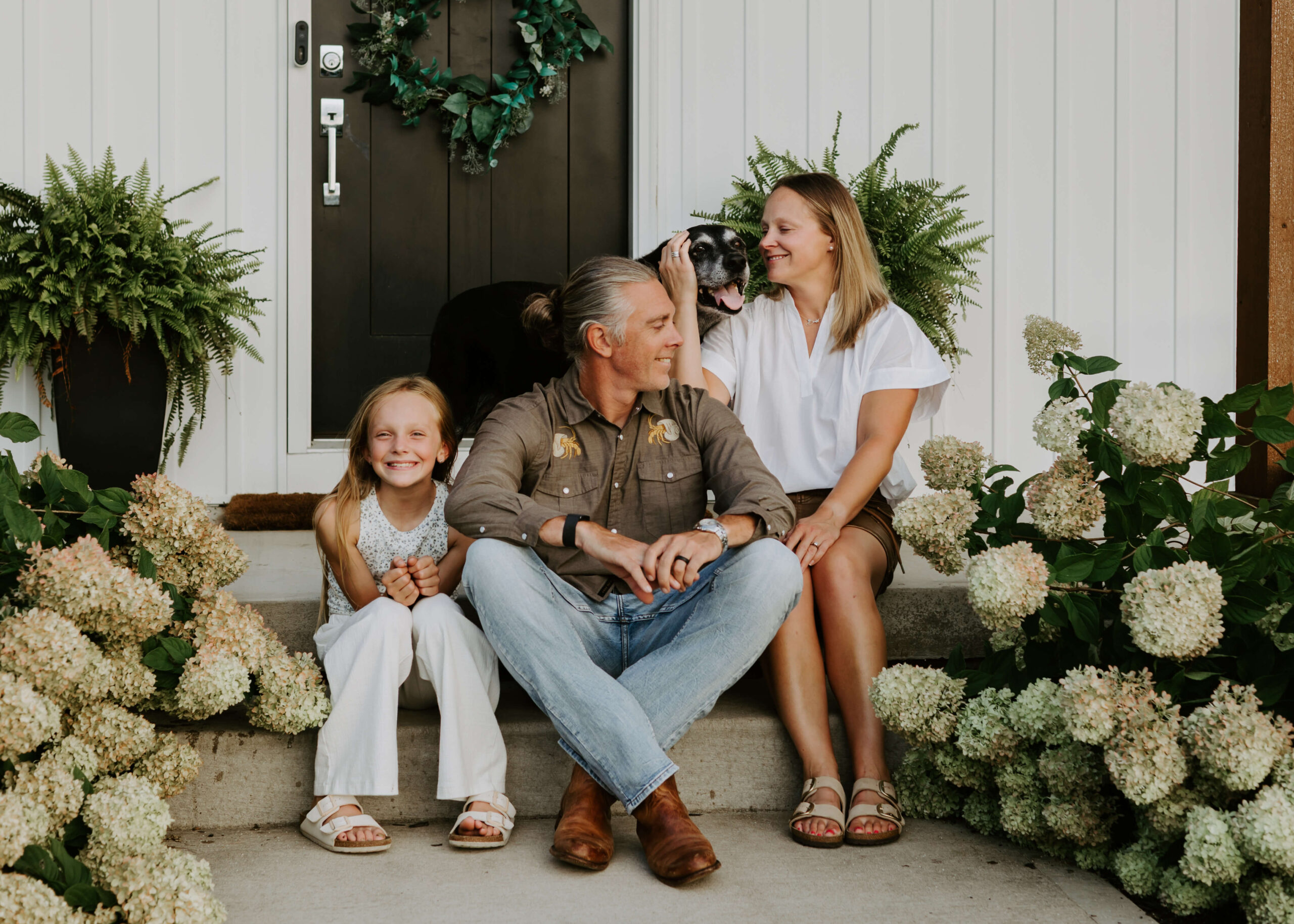Parents with young daughter sitting in front of their home in Pittsburg PA for a family photoshoot