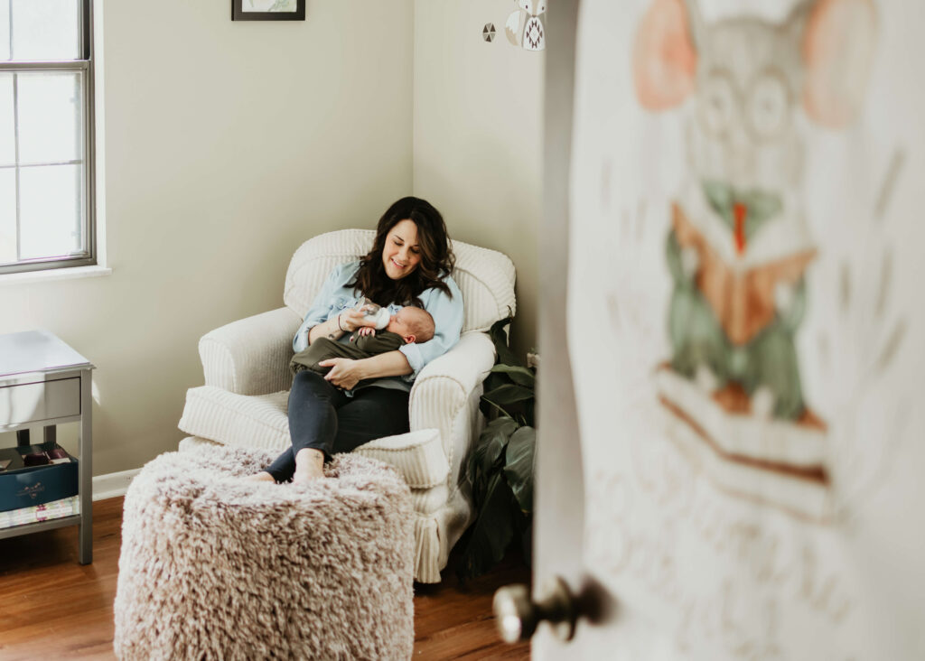 Young mother holding newborn baby at home during photo session